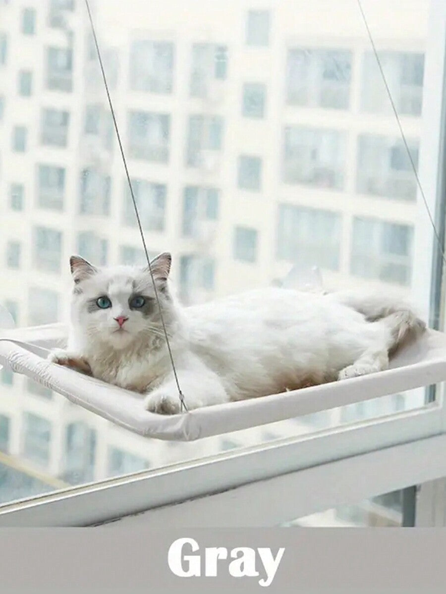 Multicolor hanging cat window hammock bed with cozy blanket mounted on a sunny window seat.