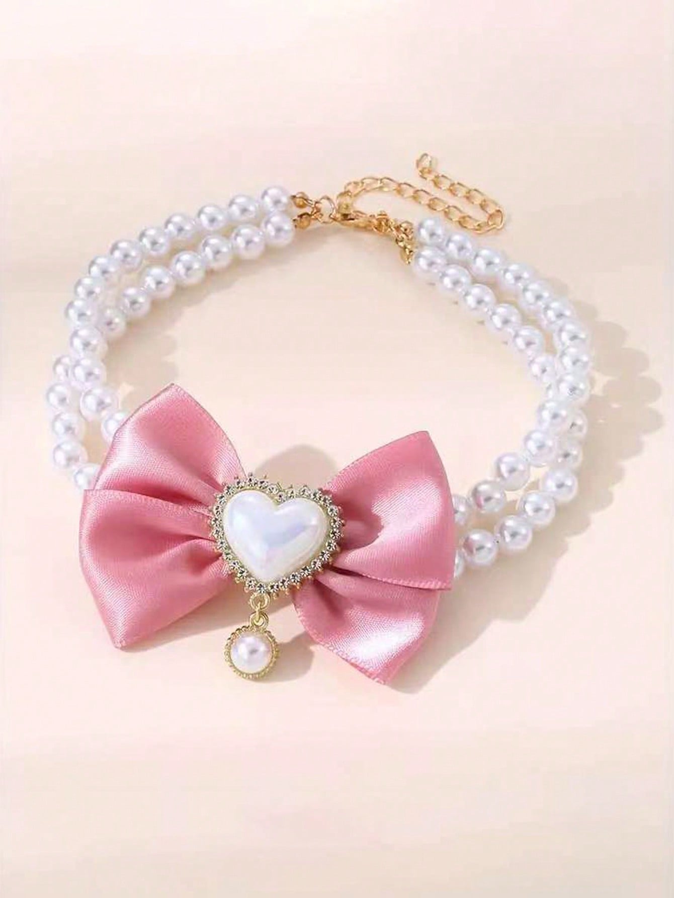 Pink faux pearl pet necklace collar with bow and heart-shaped princess-style decor for cats and dogs, made from polyester for holidays and special occasions.