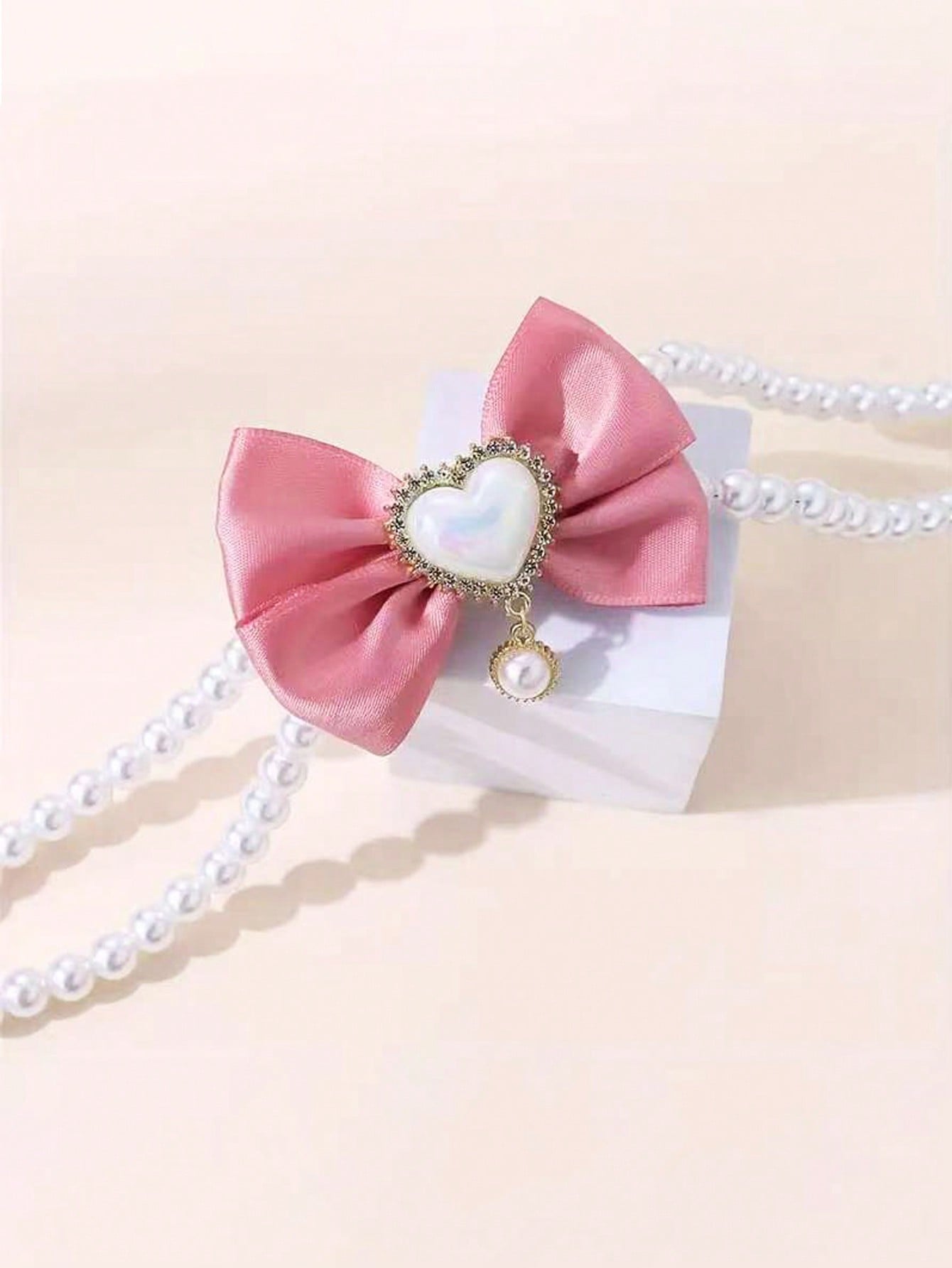 Pink faux pearl pet necklace collar with bow and heart-shaped princess-style decor for cats and dogs, made from polyester for holidays and special occasions.