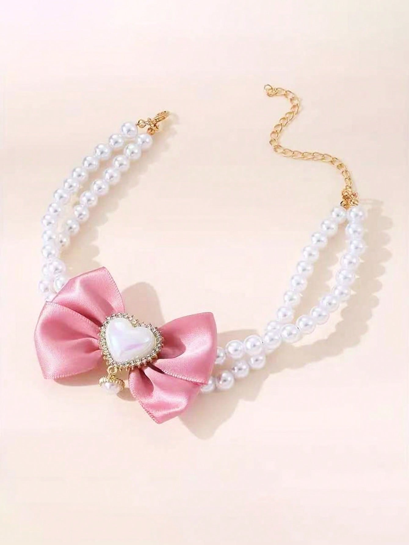 Pink faux pearl pet necklace collar with bow and heart-shaped princess-style decor for cats and dogs, made from polyester for holidays and special occasions.