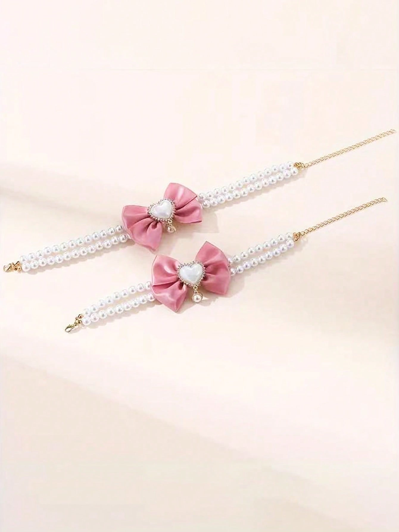 Pink faux pearl pet necklace collar with bow and heart-shaped princess-style decor for cats and dogs, made from polyester for holidays and special occasions.