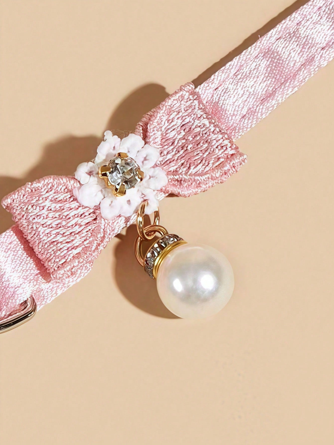 Baby pink adjustable polyester cat collar with quick release clasp, pearl pendant, white bead detail, bow, and flower decoration for kittens and cats.
