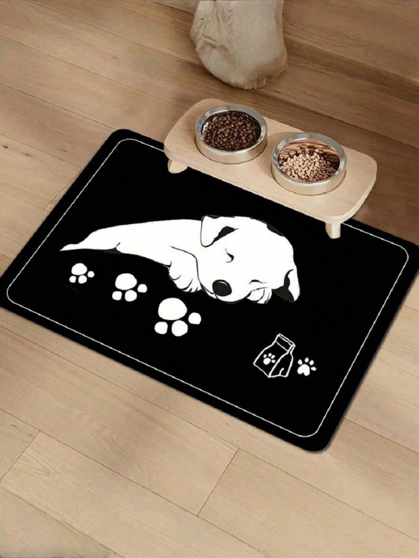 Black and white cartoon diatomite pet feeding mat placed under dog and cat food and water bowls to catch spills.