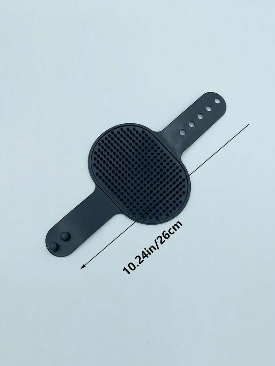 Silicone cat scratching brush with adjustable strap attached to a table leg for cat self-grooming.