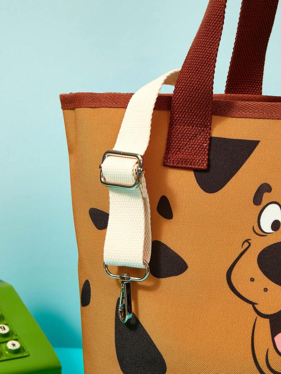 Brown soft-sided pet carrier tote bag featuring a cartoon dog print, carrying handles, and a detachable shoulder strap for travel.
