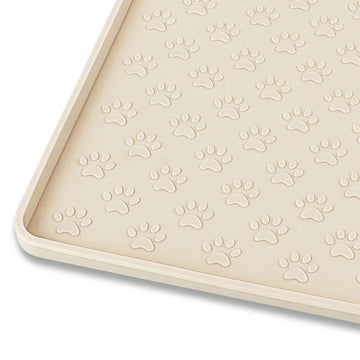 Beige silicone pet placemat with embossed paw print accents designed to catch food and water spills for dogs and cats.
