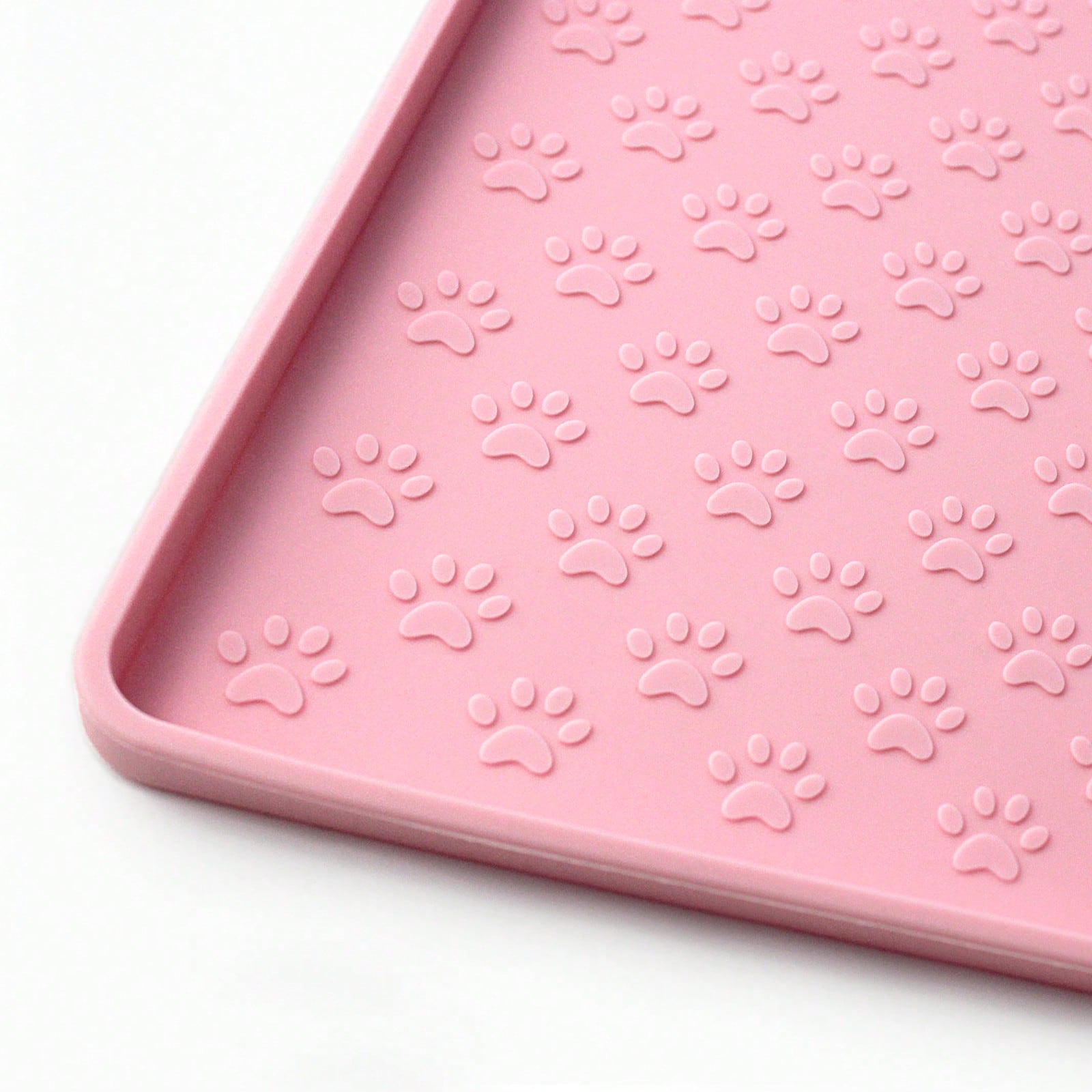 Beige silicone pet placemat with embossed paw print accents designed to catch food and water spills for dogs and cats.